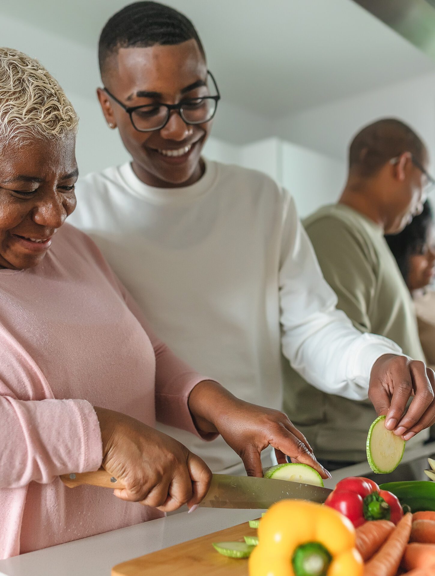 Happy African family having fun in modern kitchen preparing food recipe with fresh vegetables - Food and parents unity concept